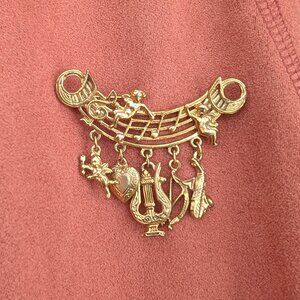 Vintage gold toned brooch with cherubs, heart, and music charms
